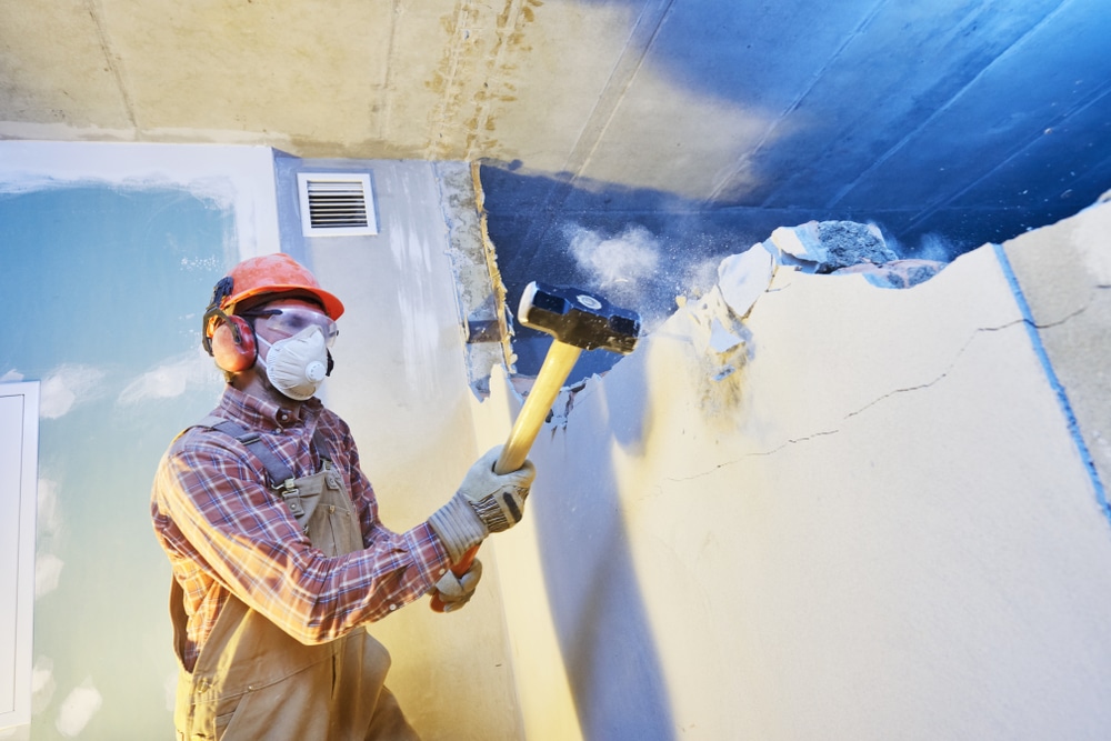 Worker With Sledgehammer At Indoor Wall